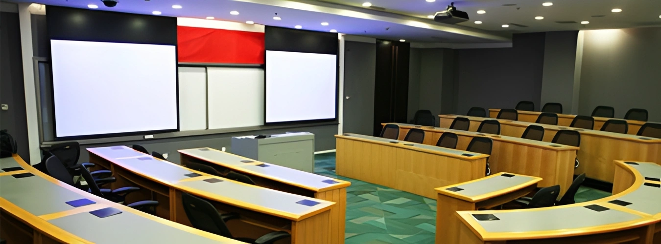 Large conference room with tables and chairs arranged in front of a projector screen, with a podium in the center