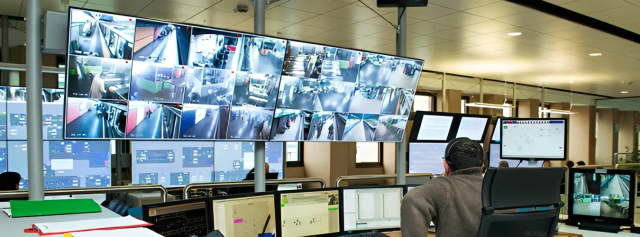 Man sitting at a desk in front of multiple monitors in a control room