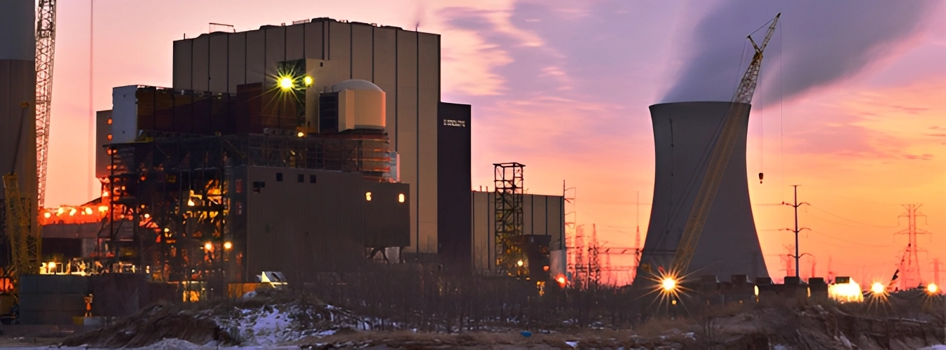 Nuclear power plant with a large building in the background, surrounded by poles, lights, towers, cranes, and other objects